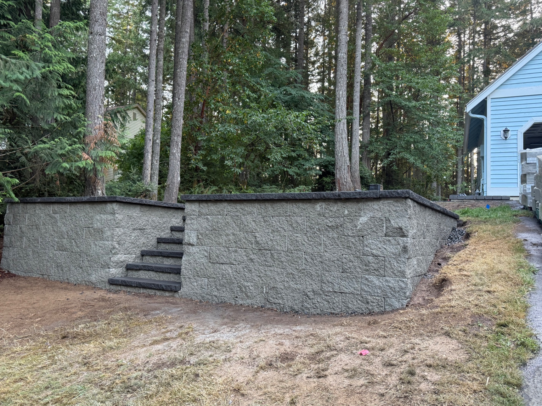 Large block retaining wall with integrated stone steps